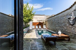 A courtyard with a pool, lounge chairs, and a wooden table. - Dimora di Catullo - Ospitalità di Charme (Palazzolo Acreide)