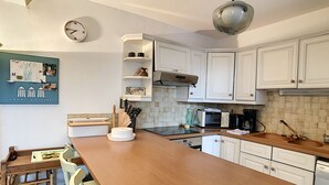 A kitchen with white cabinets, a wooden countertop, a clock, and a 'MA MAISON A LA MER' sign. - Maison LE PIGEONNIER 2 dans résidence privée (Le Plan-de-la-Tour)