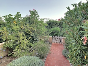 Stroll through the beautifully maintained garden, lined with lush greenery and vibrant flowers along a red brick path.