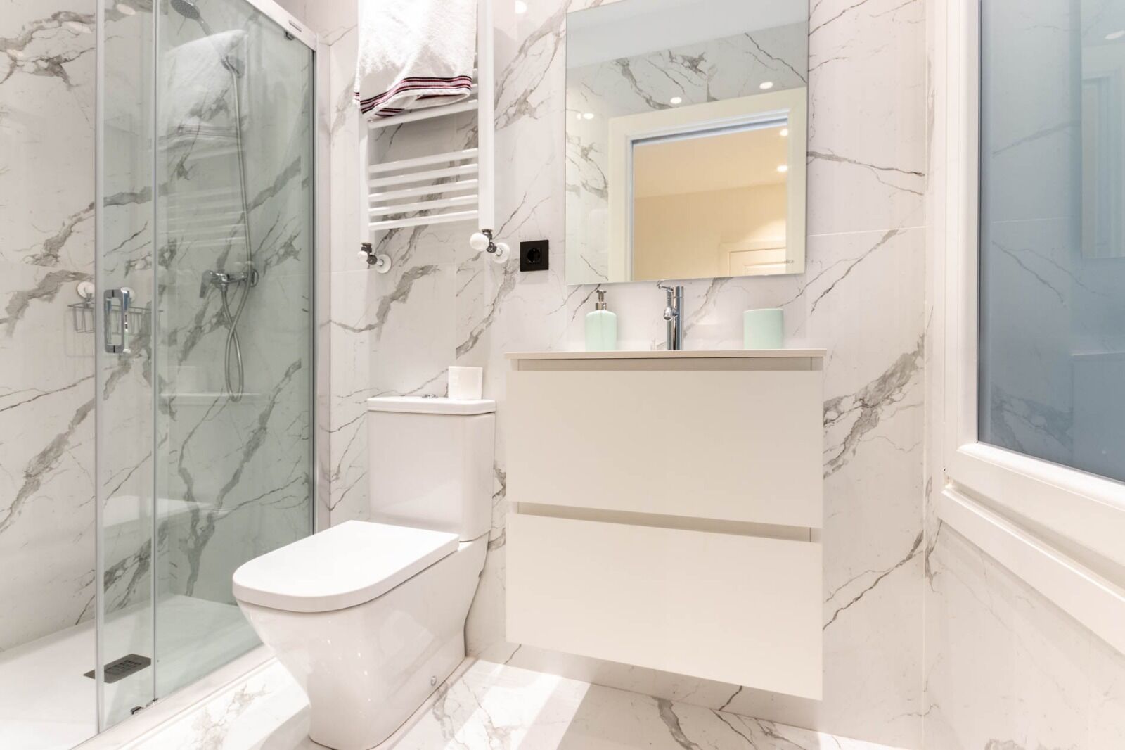 Un baño moderno con cabina de ducha de vidrio, inodoro y tocador con espejo.