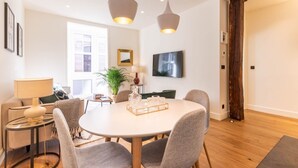 A modern dining area with a round table, grey chairs, pendant lights, and a potted plant. - LUXURY GUGGENHEIM FLAT (Bilbao)