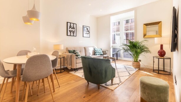 A modern living room with a dining area, a sofa, a green armchair, a coffee table, and a potted plant. - LUXURY GUGGENHEIM FLAT (Bilbao)
