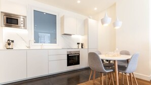 A modern kitchen with white cabinetry, a built-in oven, a microwave, and a window above the sink. - LUXURY GUGGENHEIM FLAT (Bilbao)