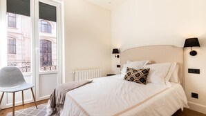 A hotel room with a bed, a chair, a window, and a radiator. - LUXURY GUGGENHEIM FLAT (Bilbao)