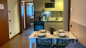 A compact kitchen with a dining table set for two, a microwave above the stove, and a small potted plant on the table. - 2 bedroom apartment-Expo Residence Rho (RHO)
