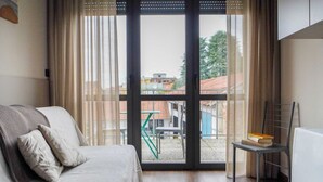 A bedroom with a bed, a chair, a radiator, and a view through a window. - 2 bedroom apartment-Expo Residence Rho (RHO)