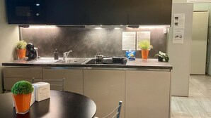 A modern kitchen with a dark countertop, stainless steel appliances, and potted plants. - Bilocale Residence La Red R1 (RHO)