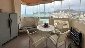 Ein Balkon mit Blick auf eine Stadtlandschaft und das Meer, ausgestattet mit einem Tisch und Stühlen sowie einem Kühlschrank.