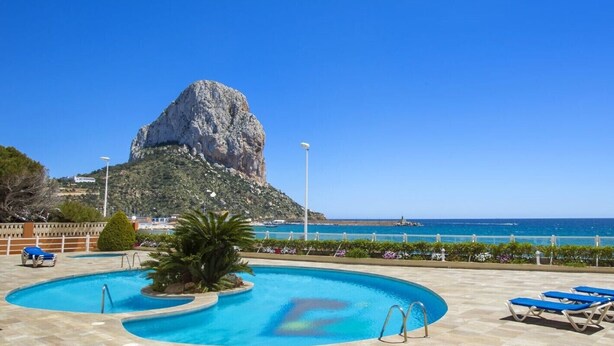 Ein Schwimmbecken mit Blick auf einen Berg und das Meer.