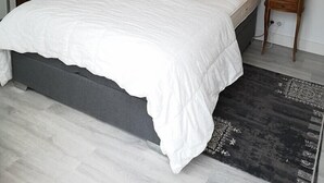 Een slaapkamer met een bed, twee nachtkastjes met lampen, een kledingkast en een lijst met een schilderij aan de muur.