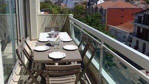 Een balkon met een eettafel, met uitzicht op een woonwijk.
