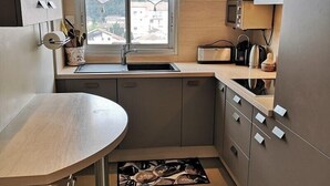 Een kleine keuken met raam, een gootsteen, een magnetron en een broodrooster.