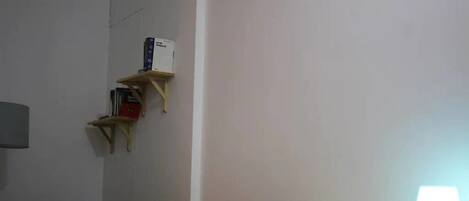Una habitación con un escritorio de madera, una silla, una lámpara y una estantería con libros.