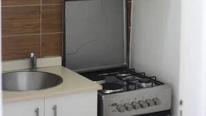 Uma cozinha compacta com armários brancos, uma pia de aço inoxidável e um fogão a gás.