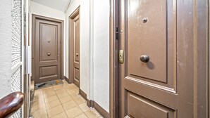 Um corredor com portas marrons e chão de azulejos.