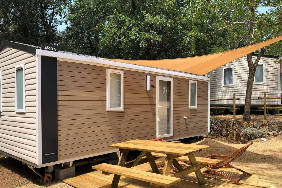 Une maison mobile équipée d’une table de pique-nique et de chaises, d’une porte et d’une fenêtre.