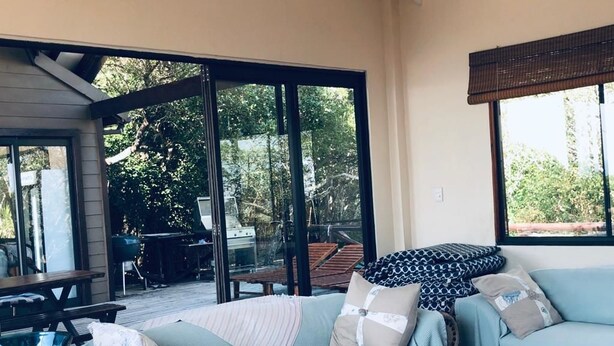 A cozy living room with a light blue sofa, a wooden coffee table, and a glass vase. - Topo Das Arvores (Ponta d'Ouro)