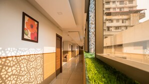 A corridor with a patterned wall, a framed artwork, and a green artificial grass area. - Oak Field Inn (Kanayannur)