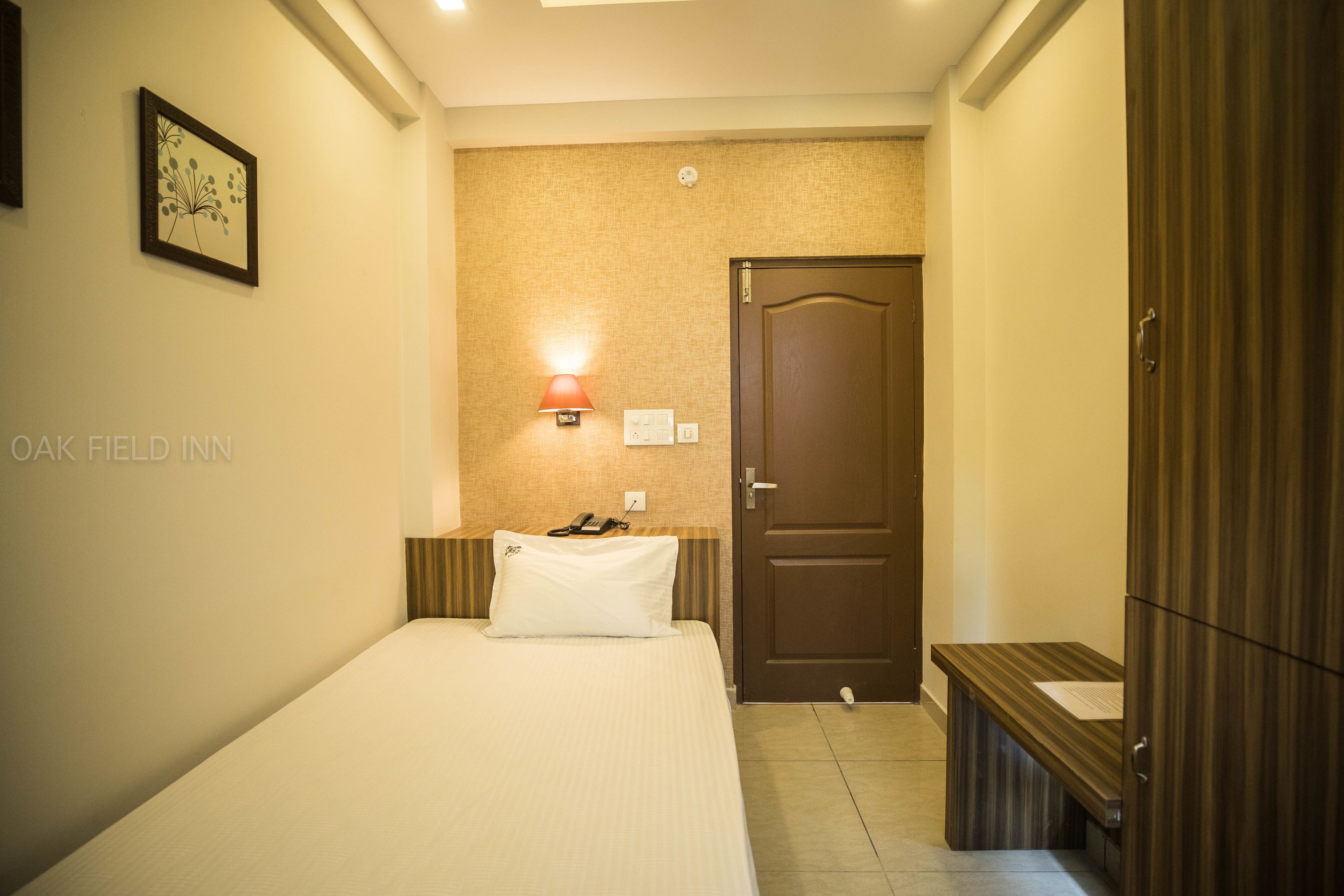 Quarto de hotel com cama, luminária e porta.