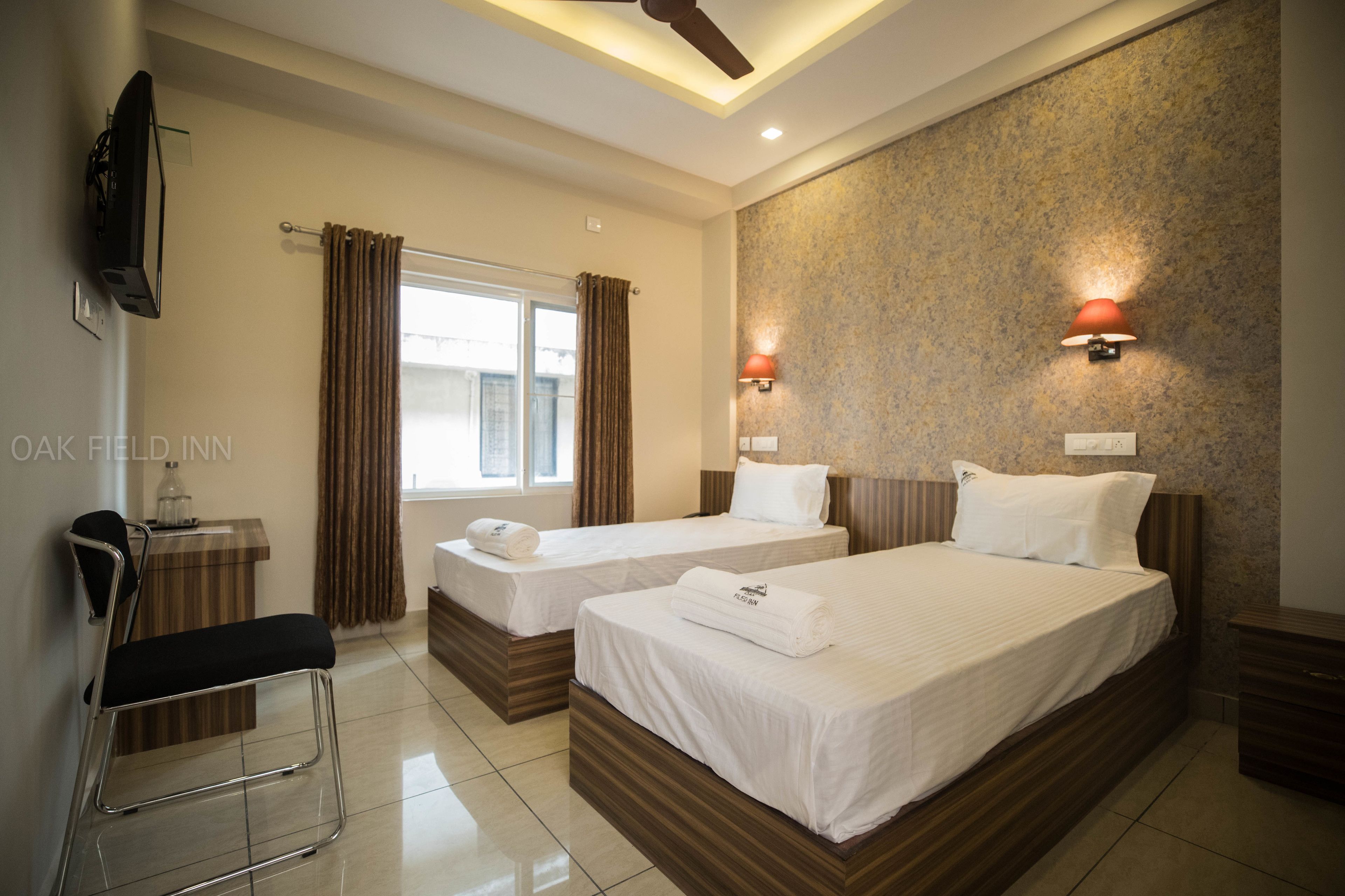 A hotel room with two beds, a desk, and a TV.