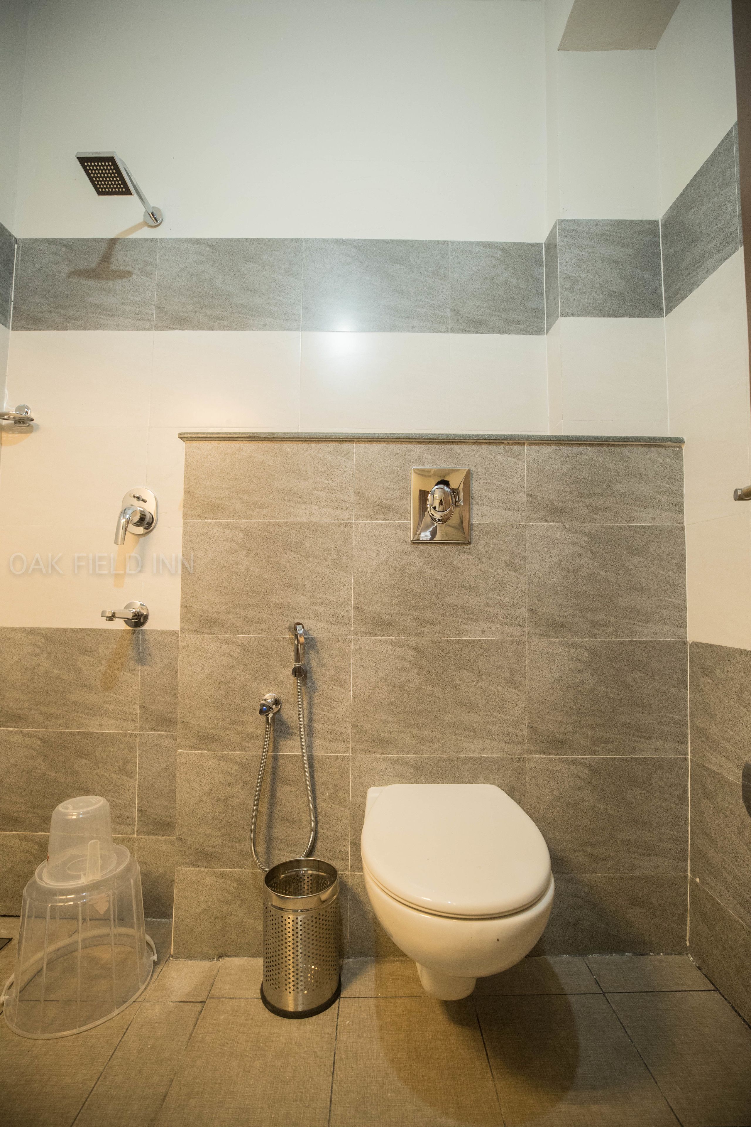 Une salle de bain avec une douche, des toilettes et une poubelle.