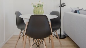 A modern room with a round dining table, two chairs, a vase with flowers, a floor lamp, and a grey sofa. - Liiiving | Bright Light Studio (Porto)