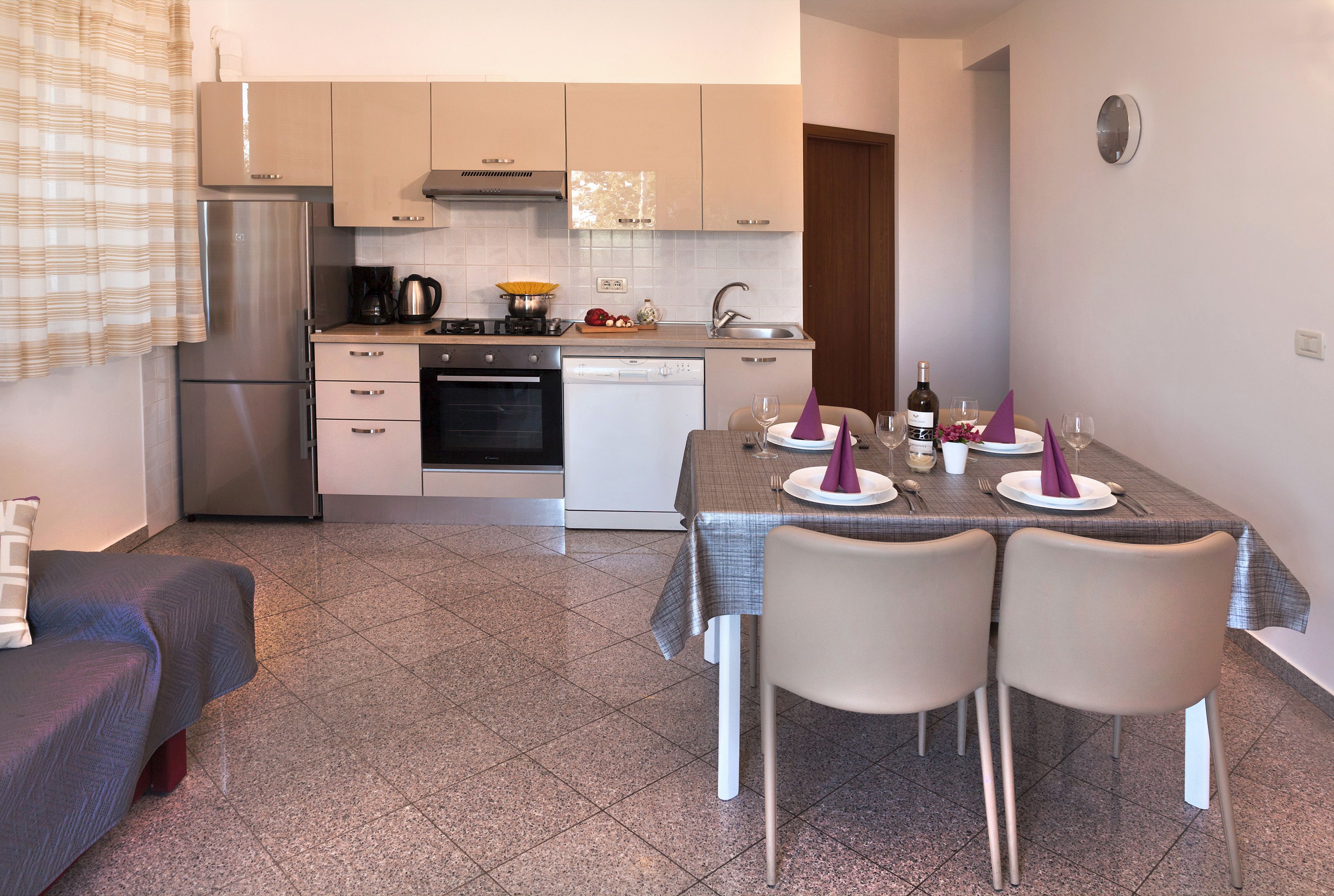 A modern kitchen with a dining area, including a refrigerator, stove, and dishwasher.