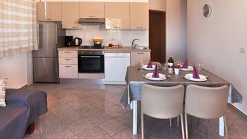A modern kitchen with a dining area, including a refrigerator, stove, and dishwasher.