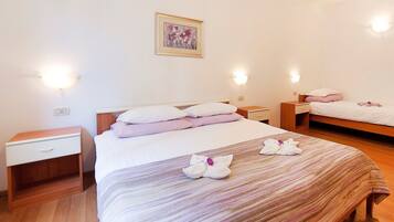 A hotel room with a large bed, two bedside tables, a nightstand, and a wall-mounted light fixture.