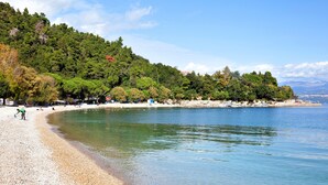 A beach with clear water, pebbles, and trees. - Villa Lidija (Lovran)