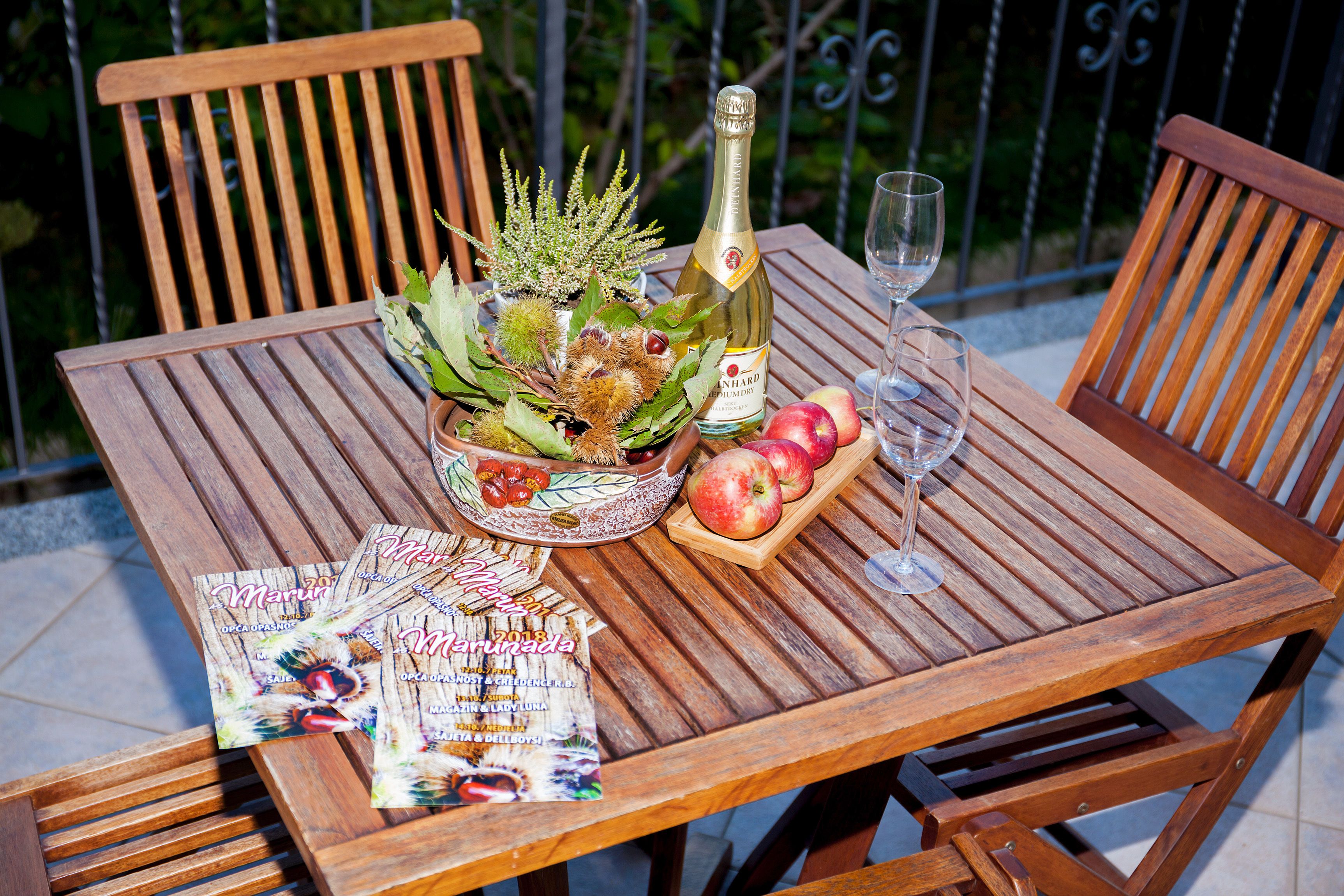 Ein Holztisch mit einer Champagnerflasche, einem Glas und einer Obstschale.