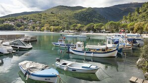 A marina with several boats docked, surrounded by lush greenery and mountains in the background. - Villa Lidija (Lovran)