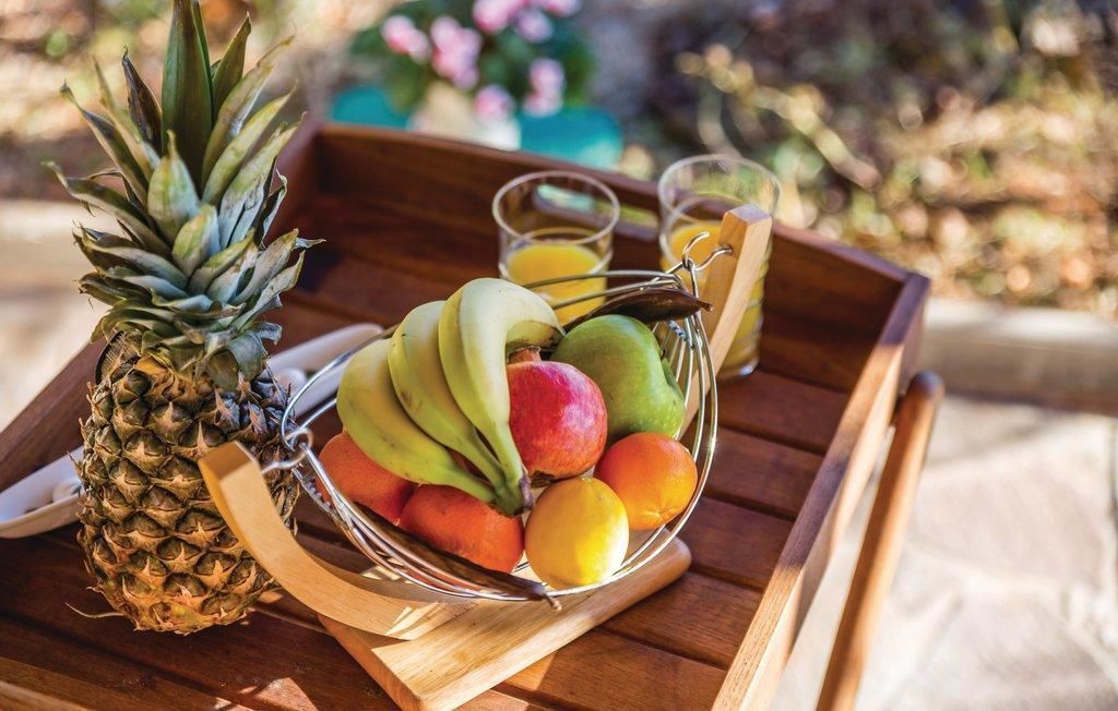 A wooden tray with a fruit bowl containing bananas, apples, and oranges, and a pineapple.