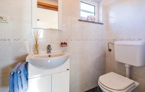 Ein Badezimmer mit einem weißen Waschbecken, einer Toilette und einem Spiegel über dem Waschbecken.