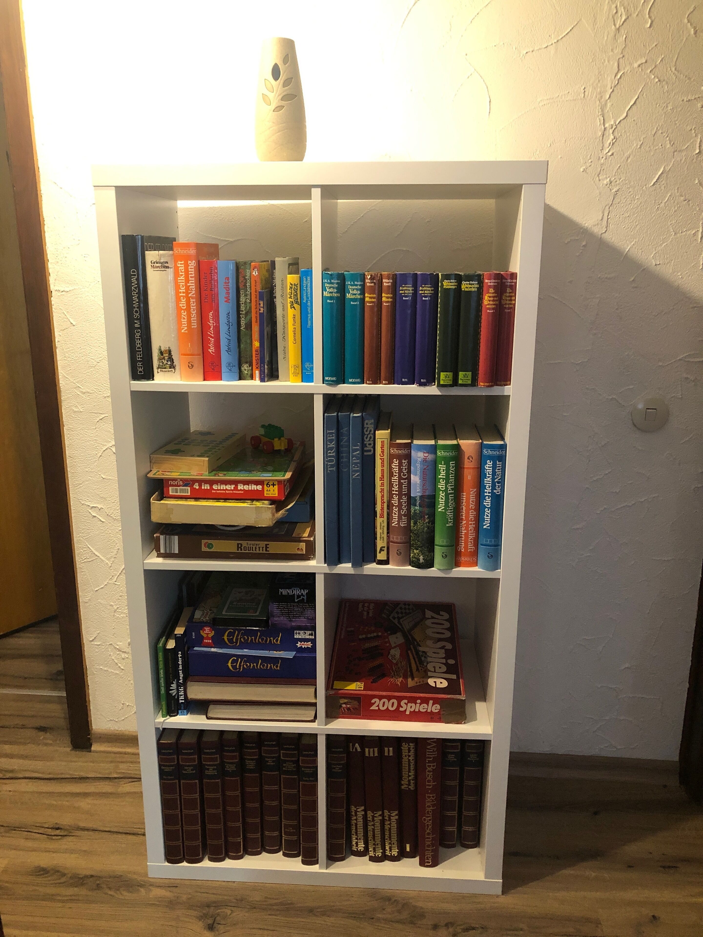 A bookshelf with various books and a game box.