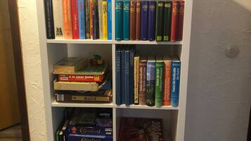 A bookshelf with various books and a game box.