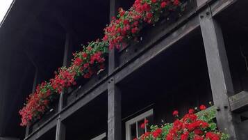 Un edificio con una facciata in legno scuro e numerosi balconi decorati con fiori rossi.