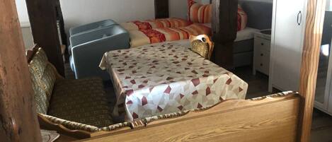 Un lit en bois avec une couvre-lit à motifs, une chaise bleue et une petite table avec un coussin.