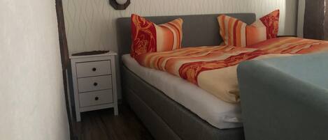 A bedroom with a bed, a nightstand, and a wall-mounted clock.