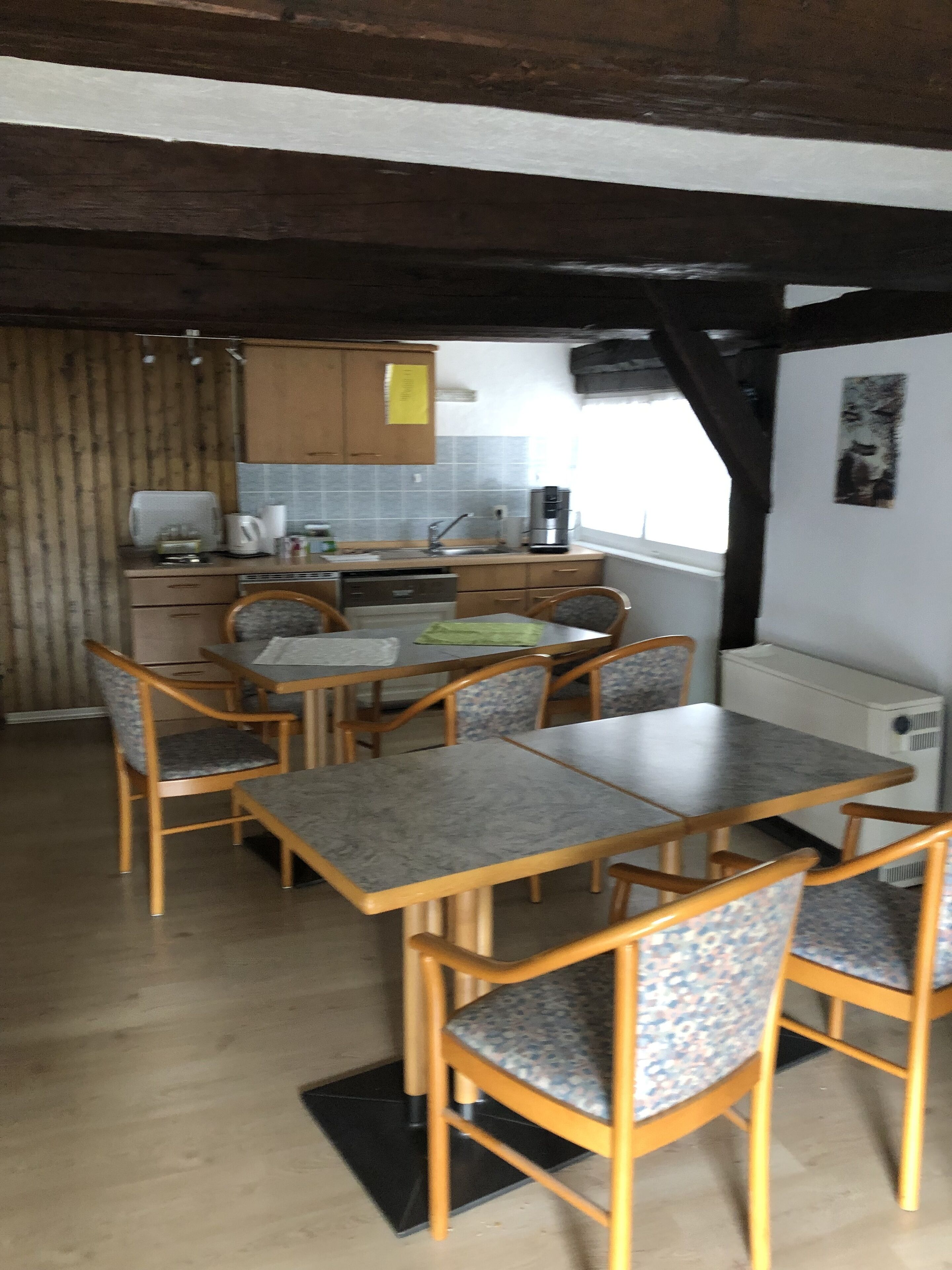 A kitchen with wooden cabinets, a countertop, and a dining area with a table and chairs.