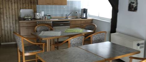 A kitchen with wooden cabinets, a countertop, and a dining area with a table and chairs.