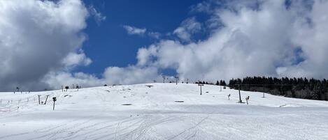 A snowy ski slope with ski lifts and tracks.
