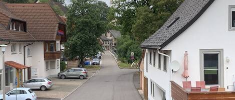 Una calle residencial con casas, coches aparcados y cielo despejado.