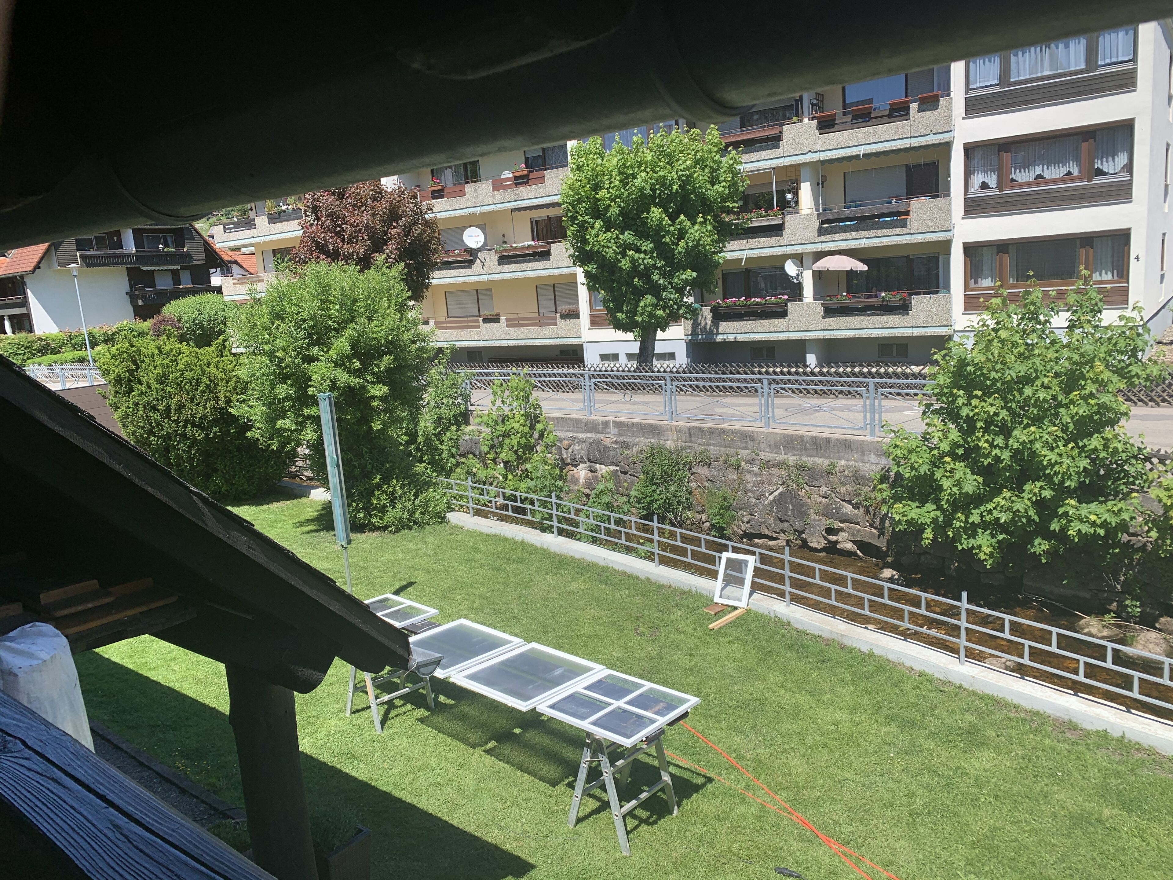 A residential area with a grassy lawn, solar panels, and a stone wall.