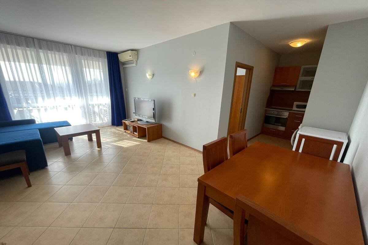Een moderne woonkamer met een bank, een houten eettafel en een televisie.