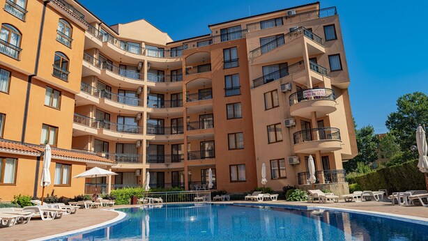 A multi-story hotel with a swimming pool, balconies, and outdoor seating.