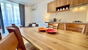 A modern kitchen with wooden cabinets, a dining table with two red plates, and a sofa in the background.