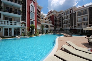 A hotel with a swimming pool, multiple balconies, and lounge chairs. - Menada Apartments in Messembria Resort (Sunny Beach)