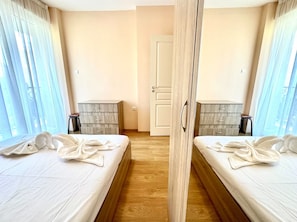 A hotel room with two beds, a wooden wardrobe, a small table, and a door. - Menada Apartments in Messembria Resort (Sunny Beach)