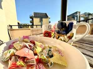 A table with a bowl of assorted candies and a floral mug. - Menada Apartments in Messembria Resort (Sunny Beach)